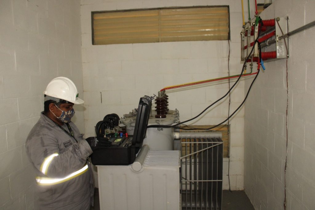 Técnico utilizando instrumento de medição junto a um transformador.