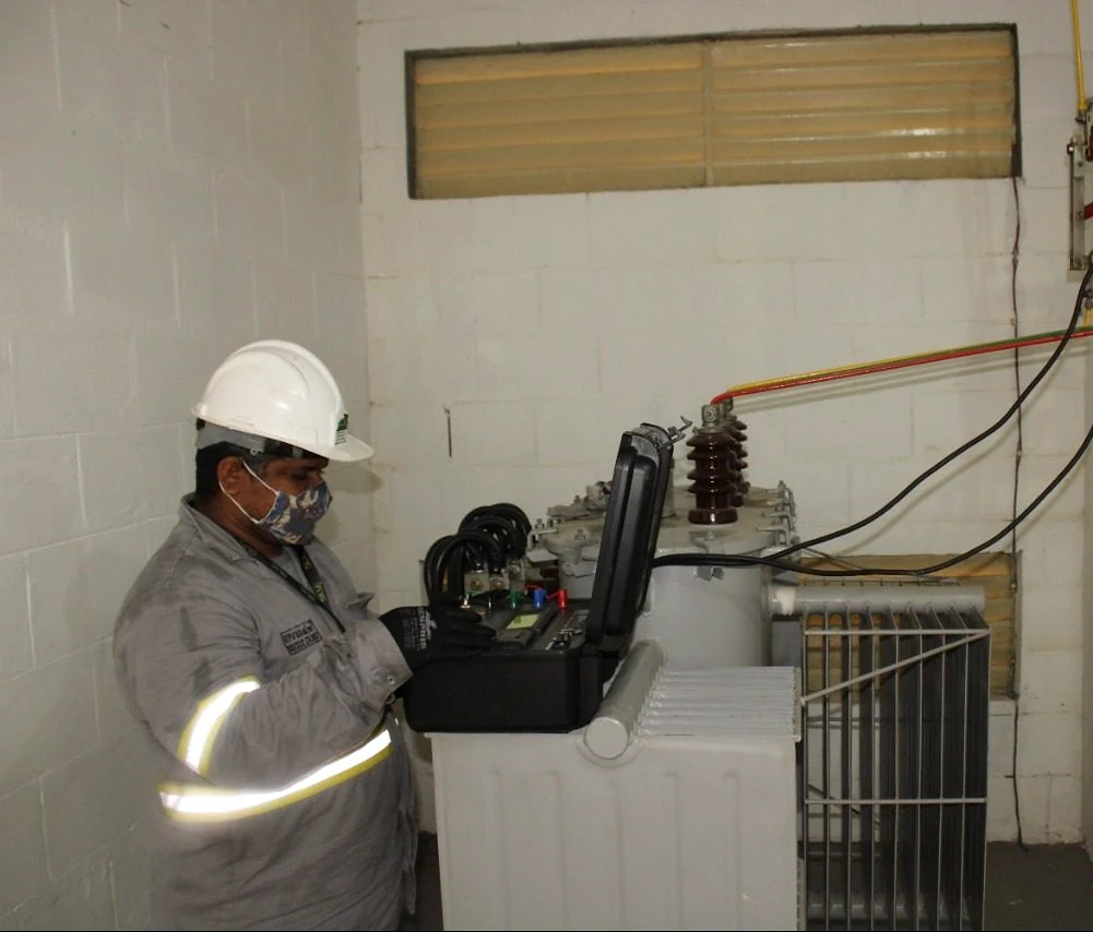 Técnico utilizando instrumento de medição junto a um transformador.
