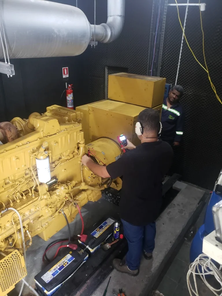 Técnico realizando manutenção junto ao motor de um grupo gerador.