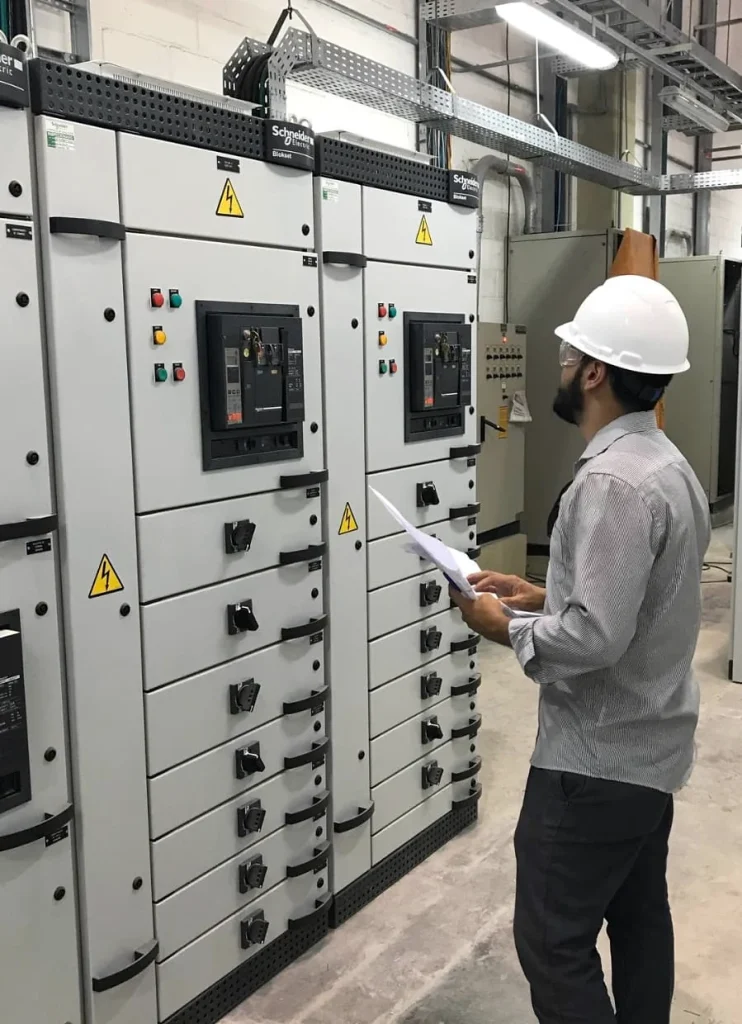 Profissional com capacete inspecionando painéis elétricos.