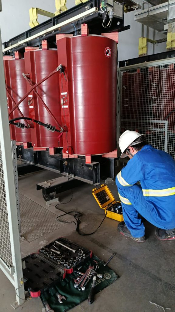 Profissional utilizando instrumento de medição junto a um transformador.